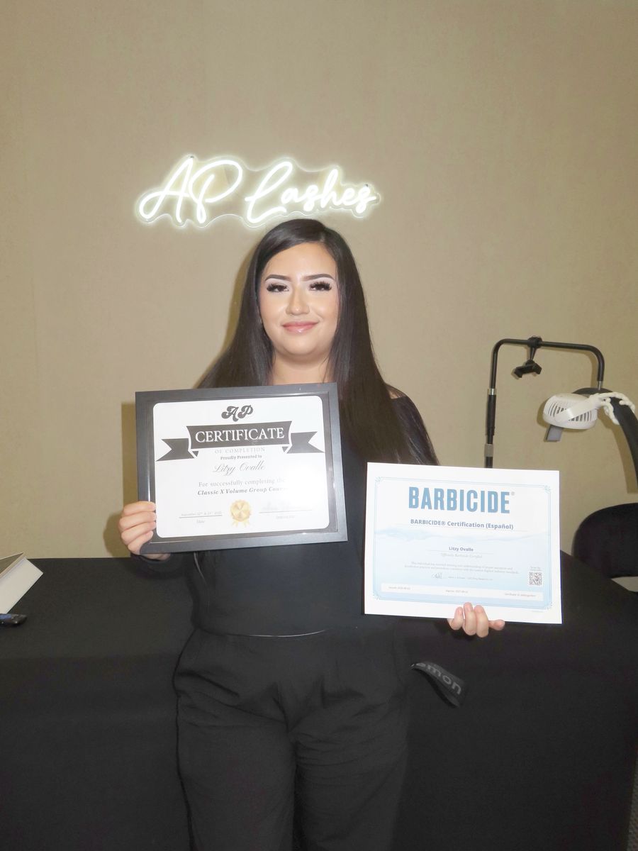 Graduate with certificates under the AP Lashes neon sign